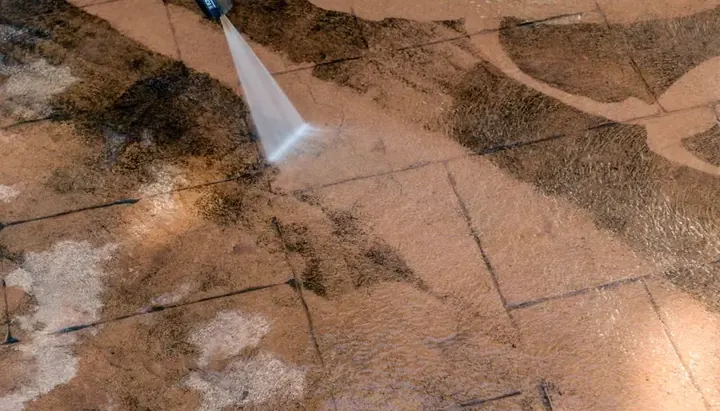 Pressure washing dirt off a paved patio